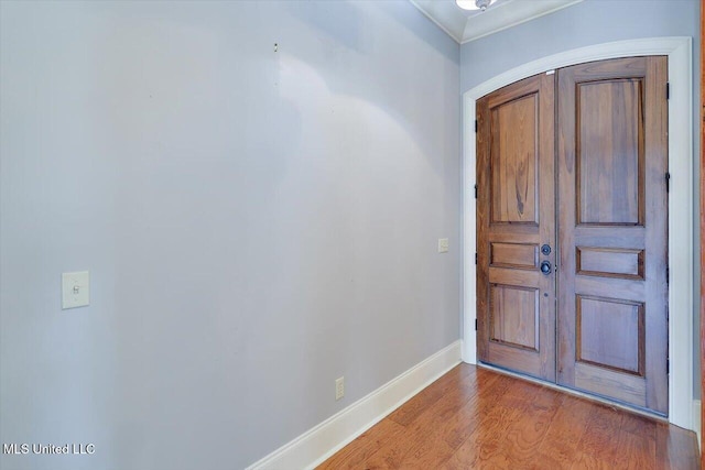 foyer with arched walkways, baseboards, and wood finished floors