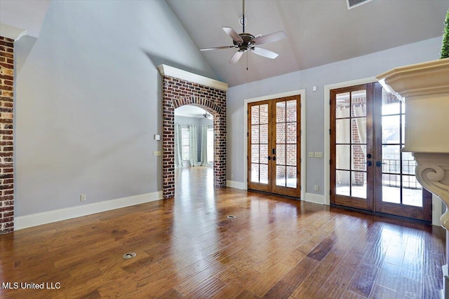 unfurnished room with ceiling fan, french doors, wood finished floors, arched walkways, and high vaulted ceiling