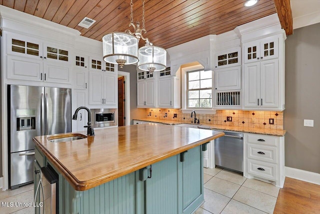 kitchen with backsplash, appliances with stainless steel finishes, white cabinets, and a sink