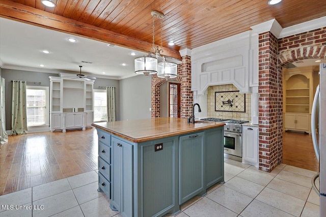 kitchen featuring crown molding, light tile patterned floors, open floor plan, and appliances with stainless steel finishes