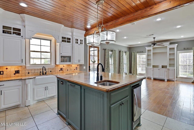 kitchen with light tile patterned floors, a ceiling fan, a sink, white cabinetry, and backsplash