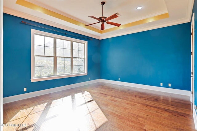 unfurnished room featuring ceiling fan, crown molding, a tray ceiling, and wood finished floors