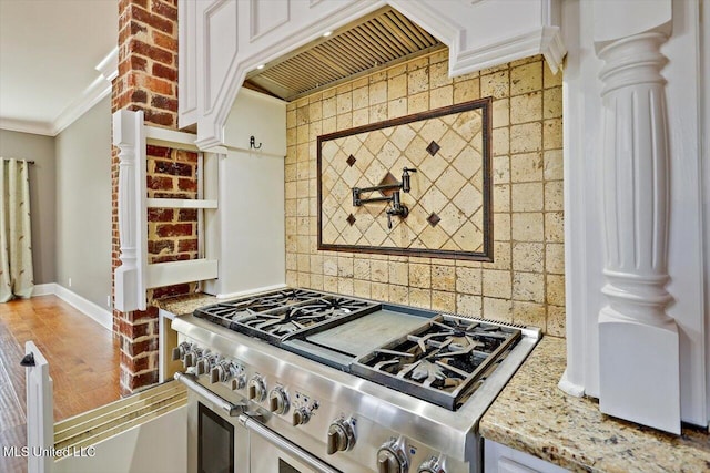 kitchen featuring light stone counters, double oven range, decorative columns, crown molding, and decorative backsplash