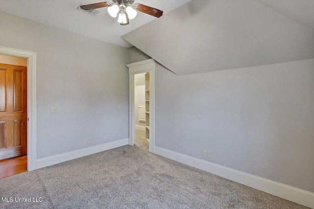 unfurnished bedroom featuring visible vents, baseboards, vaulted ceiling, carpet flooring, and a ceiling fan