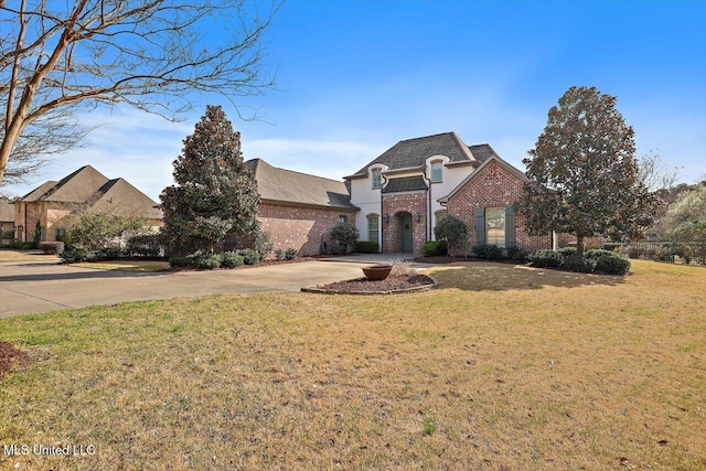 french country home with brick siding, driveway, and a front yard