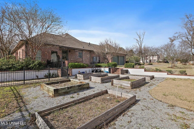 back of property with brick siding, a vegetable garden, and fence