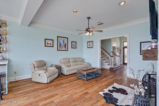 living area with stairway, ceiling fan, wood finished floors, and ornamental molding