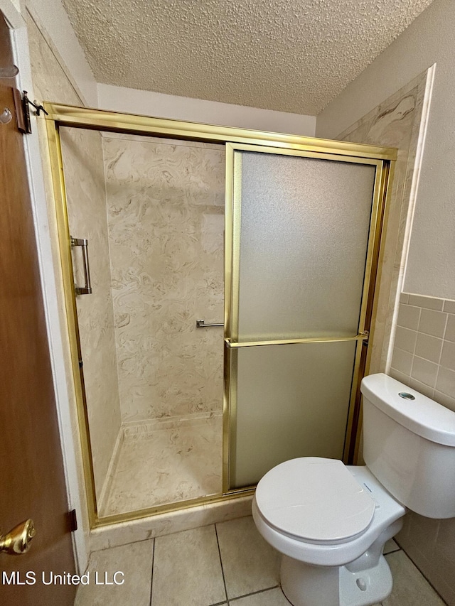 126 Faust Dr, Gulfport, MS 39503 - full bathroom with toilet, a textured ceiling, a stall shower, tile patterned floors, and tile walls