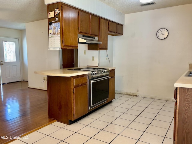 126 Faust Dr, Gulfport, MS 39503 - kitchen with stainless steel range with electric stovetop, under cabinet range hood, light countertops, a textured ceiling, and brown cabinets