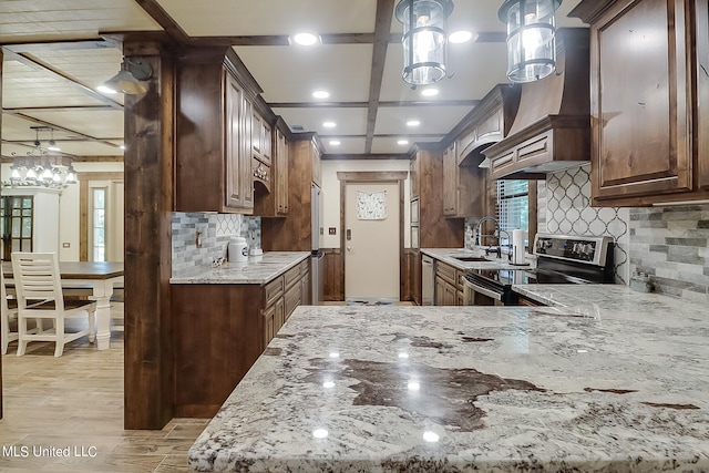 kitchen featuring sink, light stone countertops, stainless steel electric range, decorative light fixtures, and light hardwood / wood-style floors