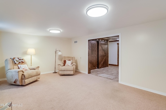 living area with a barn door and carpet