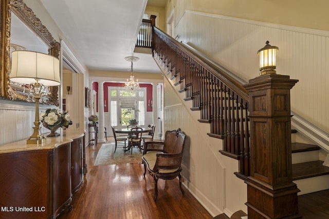 315 N St, Lexington, MS 39095 - foyer entrance featuring dark wood-style flooring, an inviting chandelier, wainscoting, a decorative wall, and stairway