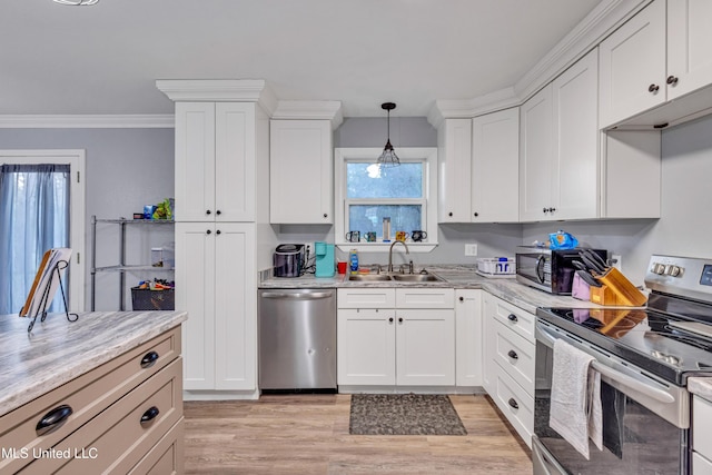 kitchen with appliances with stainless steel finishes, white cabinetry, sink, hanging light fixtures, and light stone counters