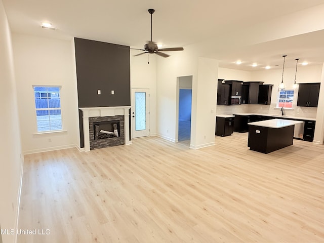 3165 Winterwood Dr, Hernando, MS 38632 - unfurnished living room featuring light wood-type flooring, a ceiling fan, a sink, a fireplace, and baseboards