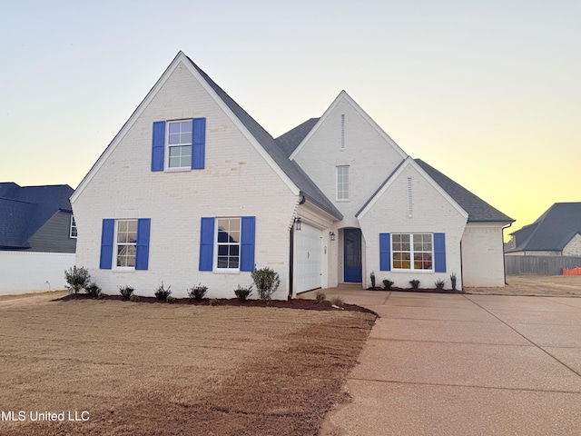 view of front of property featuring a garage, brick siding, and concrete driveway