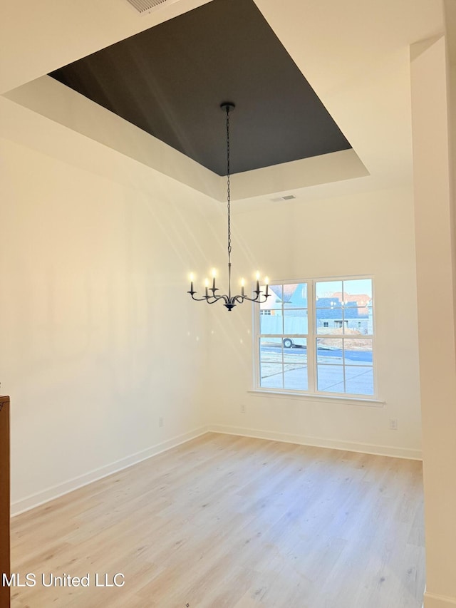 3165 Winterwood Dr, Hernando, MS 38632 - unfurnished room with a tray ceiling, baseboards, an inviting chandelier, and light wood finished floors