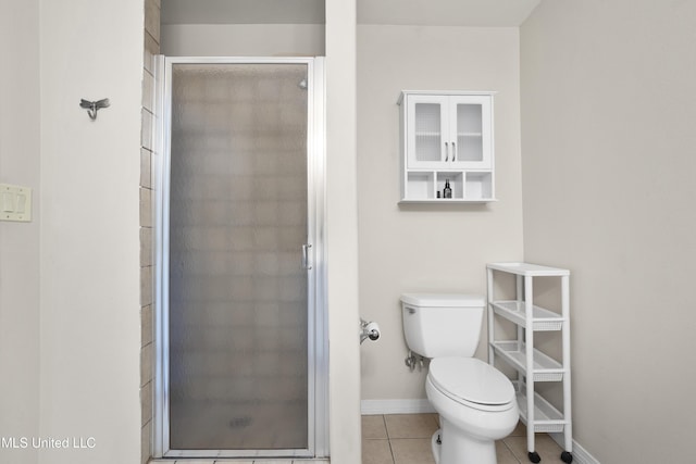 bathroom featuring tile patterned flooring, a shower with shower door, and toilet