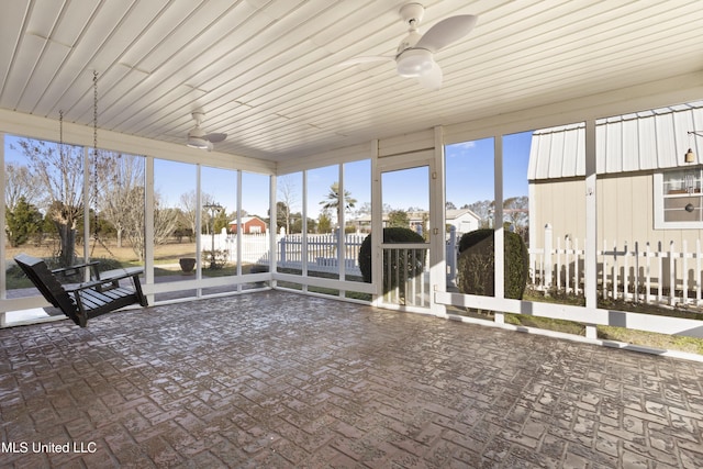 unfurnished sunroom with wood ceiling, plenty of natural light, and ceiling fan