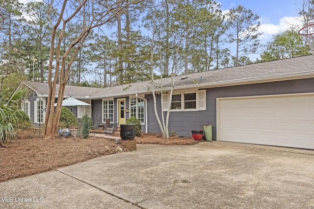 ranch-style home featuring a garage, concrete driveway, and a shingled roof