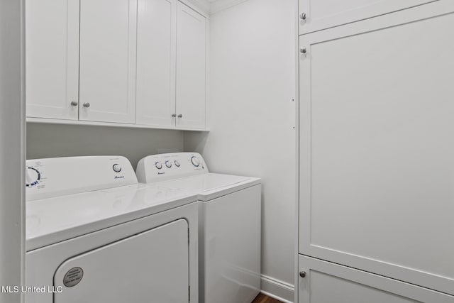 clothes washing area featuring cabinet space and washer and clothes dryer