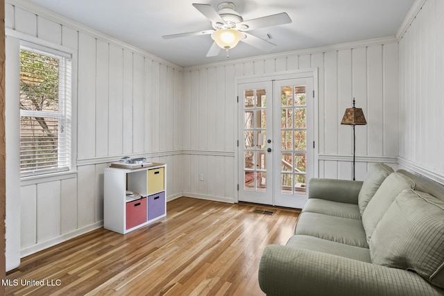 sitting room with french doors, visible vents, ornamental molding, ceiling fan, and light wood-type flooring