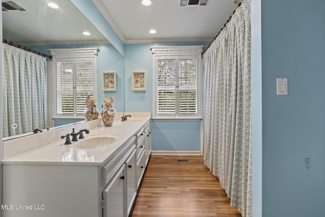 full bathroom with double vanity, wood finished floors, a sink, and crown molding