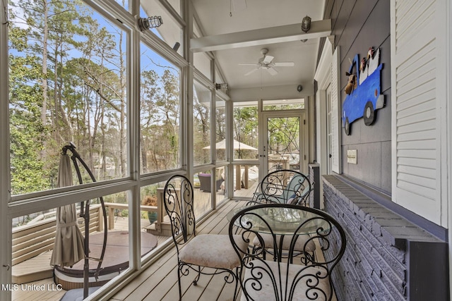 sunroom / solarium featuring ceiling fan and beamed ceiling