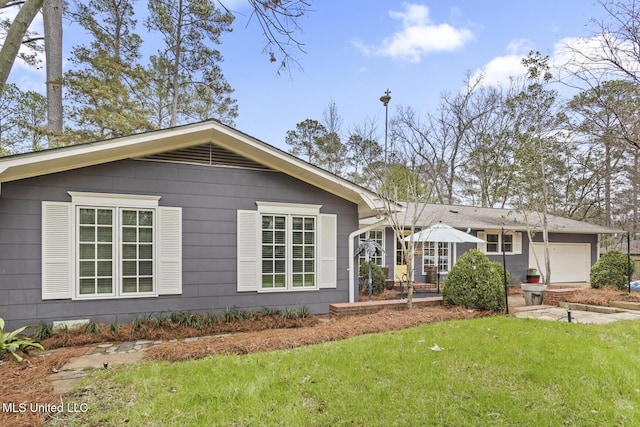 back of property featuring a garage and a yard