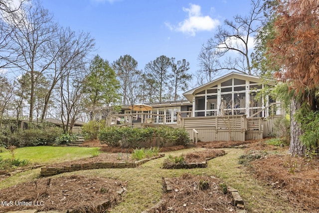 rear view of house featuring a deck, a lawn, and a sunroom