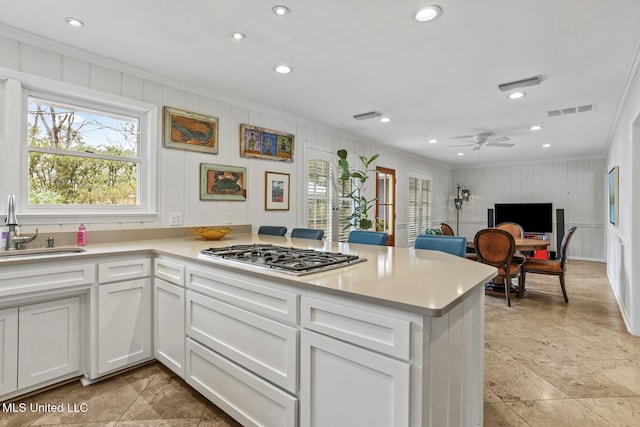 kitchen with stainless steel gas cooktop, a sink, white cabinetry, light countertops, and crown molding