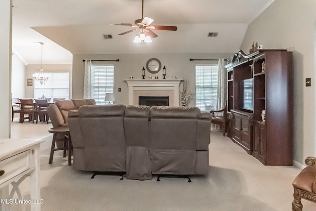 living room featuring vaulted ceiling, light colored carpet, a healthy amount of sunlight, and ceiling fan with notable chandelier