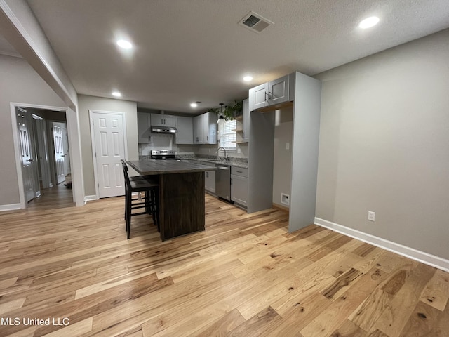 kitchen with gray cabinets, visible vents, a center island, a sink, and stainless steel appliances