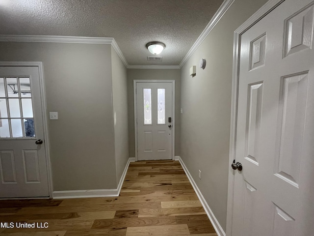 doorway with visible vents, ornamental molding, baseboards, a textured ceiling, and light wood finished floors