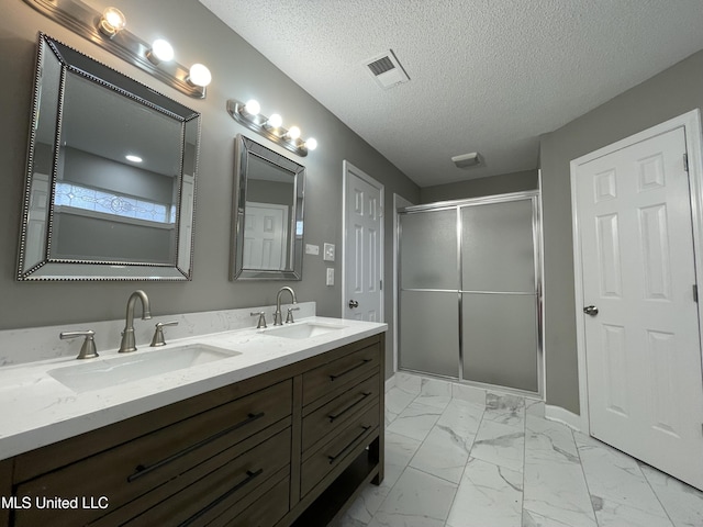 full bathroom featuring double vanity, a sink, marble finish floor, and a stall shower