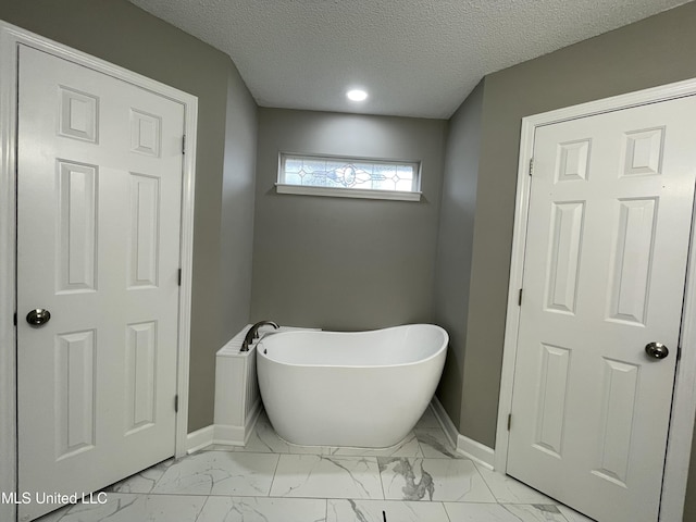 bathroom featuring baseboards, marble finish floor, and a soaking tub