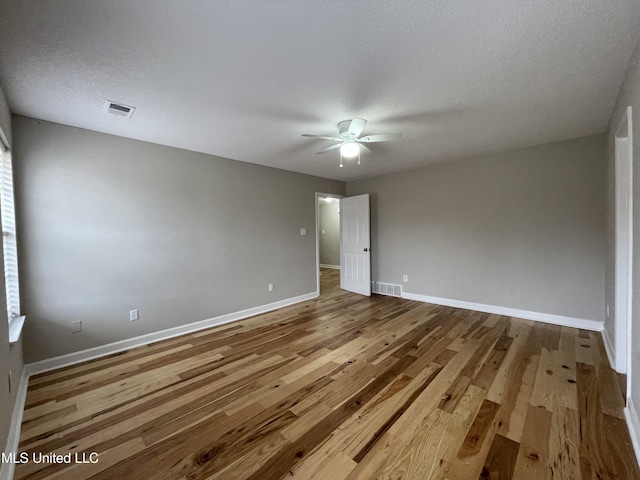 spare room featuring a ceiling fan, baseboards, visible vents, and wood finished floors