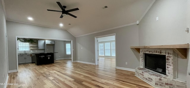 unfurnished living room with light wood-type flooring, ornamental molding, ceiling fan, and a fireplace