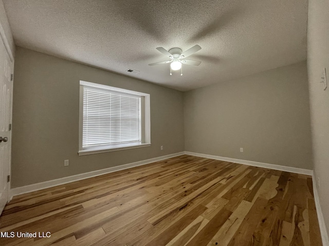 unfurnished room with a textured ceiling, ceiling fan, baseboards, and wood finished floors