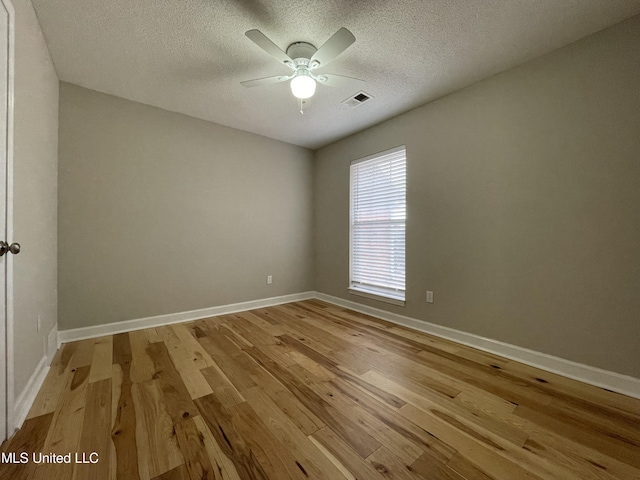 unfurnished room featuring a textured ceiling, visible vents, ceiling fan, and light wood-style floors