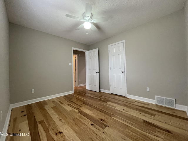 unfurnished bedroom featuring a ceiling fan, baseboards, visible vents, and wood finished floors