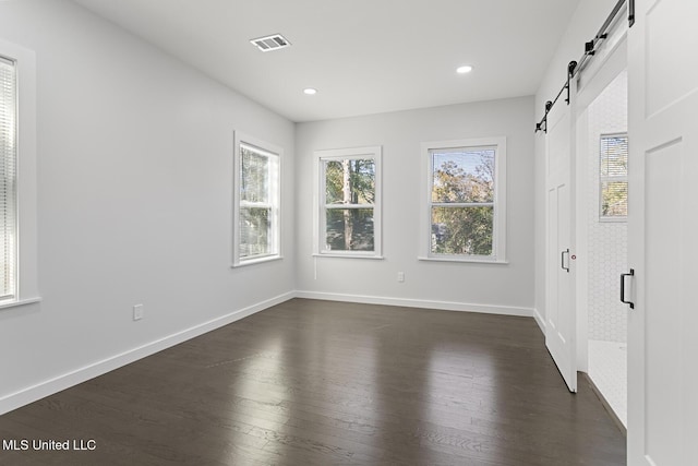 empty room featuring a barn door and dark hardwood / wood-style flooring