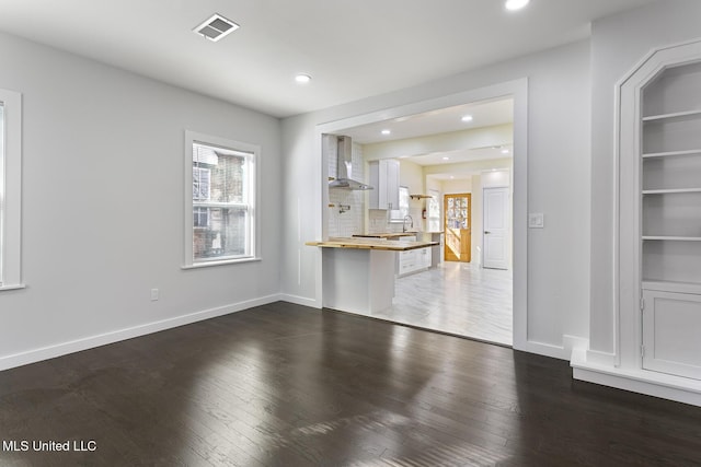 unfurnished living room with built in shelves, sink, and dark wood-type flooring