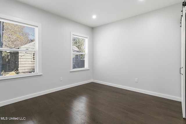 unfurnished room featuring a barn door and dark hardwood / wood-style floors