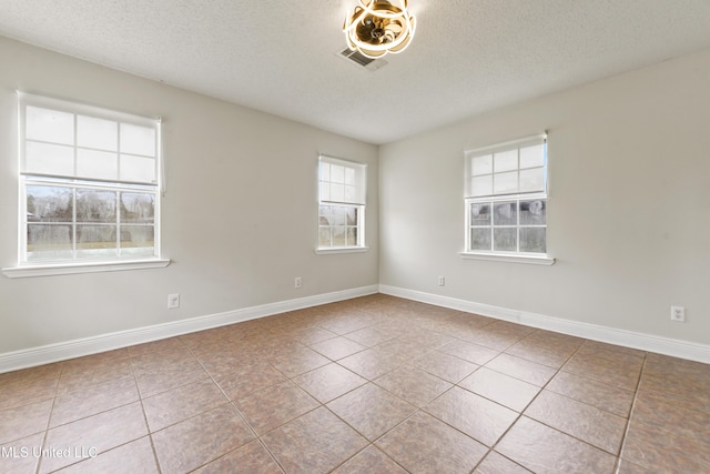 unfurnished room featuring a textured ceiling, tile patterned floors, visible vents, and baseboards