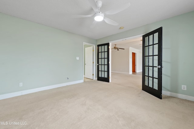 carpeted spare room with ceiling fan, french doors, and baseboards