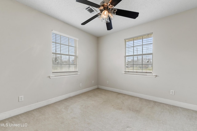 carpeted spare room with a textured ceiling, baseboards, visible vents, and a healthy amount of sunlight