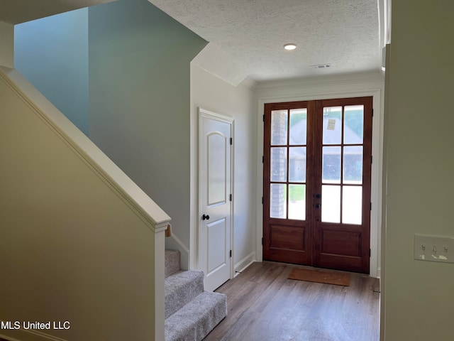 foyer with french doors, light hardwood / wood-style floors, and a textured ceiling