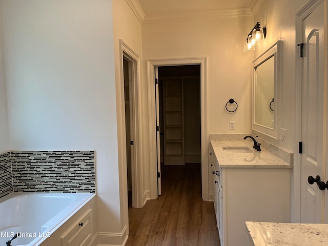 bathroom with vanity, a tub, wood-type flooring, and ornamental molding