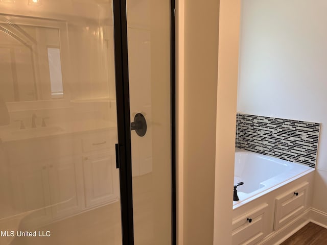 bathroom with tasteful backsplash, independent shower and bath, sink, and hardwood / wood-style floors