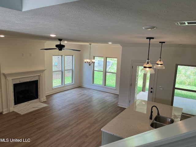 kitchen with dark hardwood / wood-style flooring, a high end fireplace, pendant lighting, crown molding, and sink